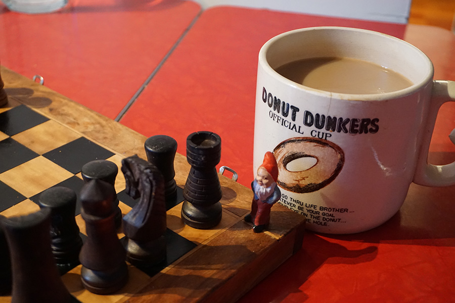 photo of a garden gnome on a chess set with a coffee cup. British Columbia, Canada