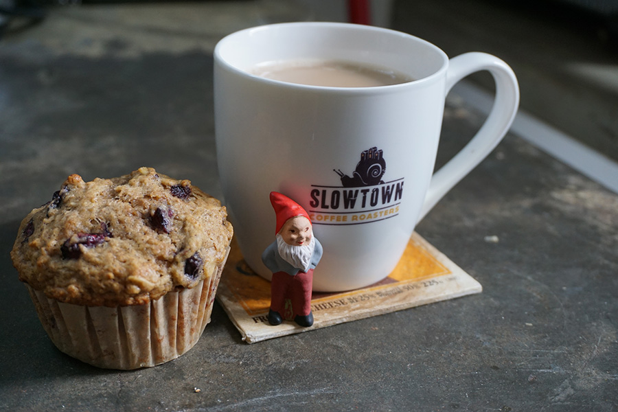 Photo of a coffee cup, a muffin, and a gnome.